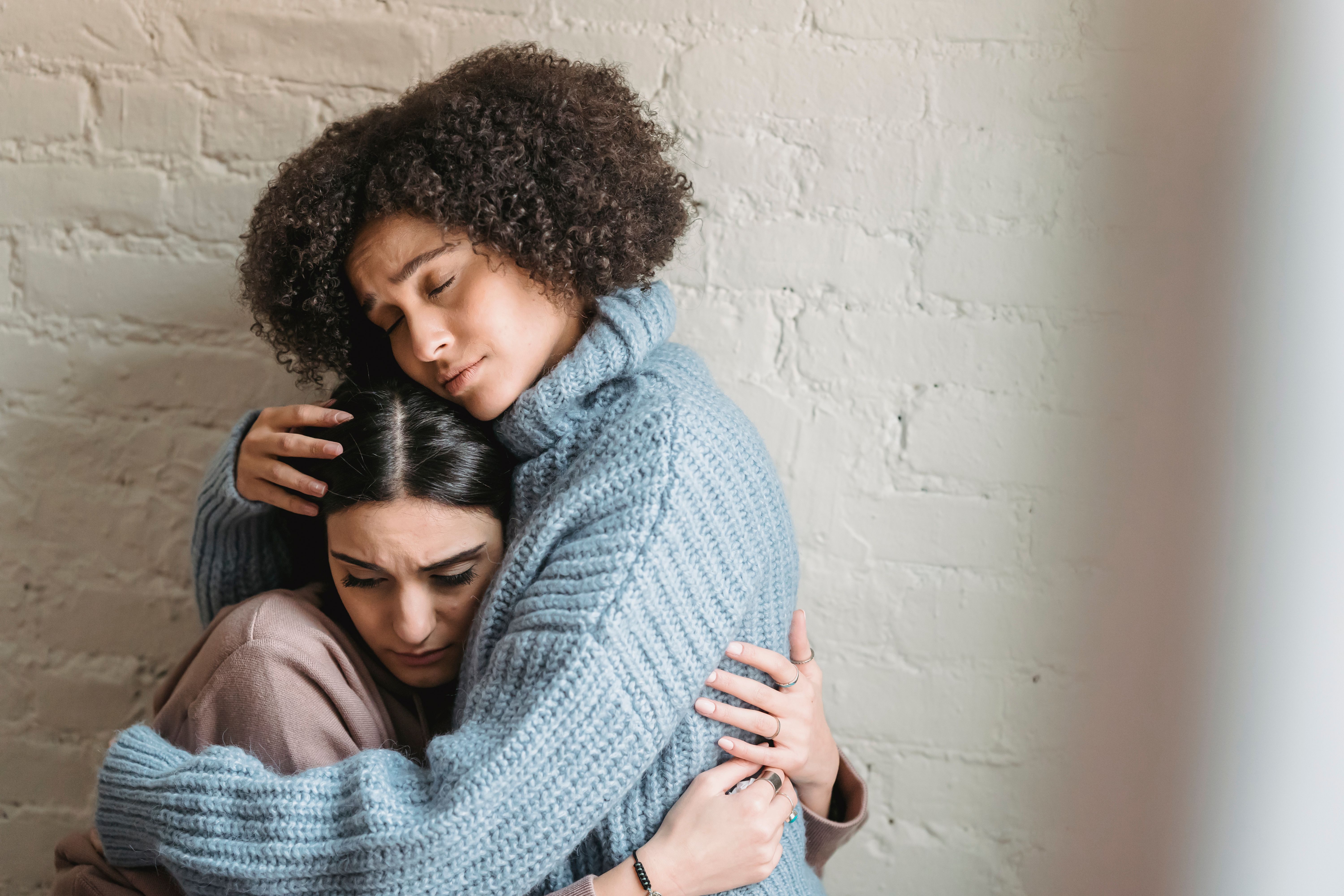 A woman comforting her friend in a warm hug during a vulnerable emotional moment