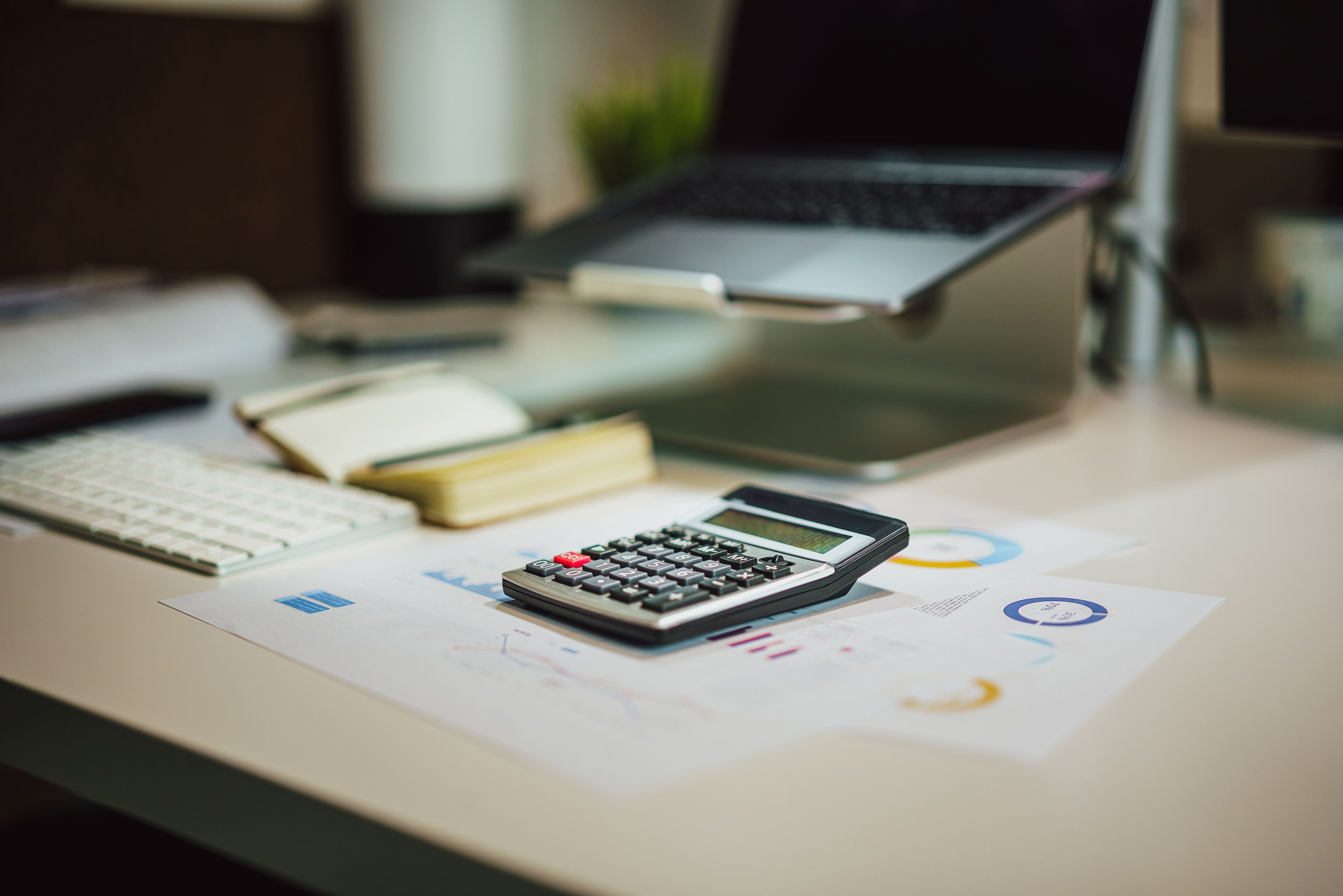 Laptop, calculator, and financial documents arranged on a modern office desk