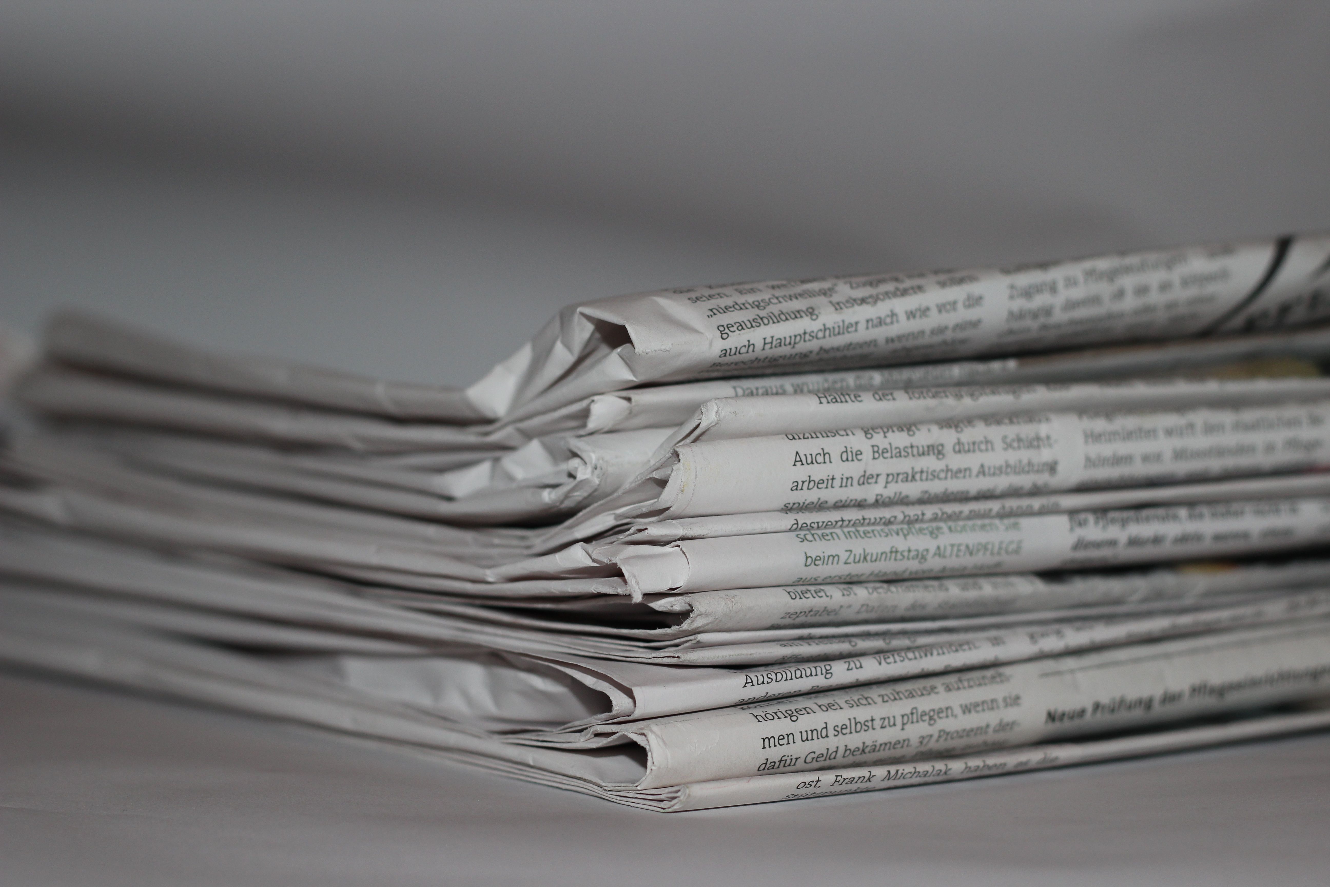 Close-up of folded newspapers, representing news and journalism