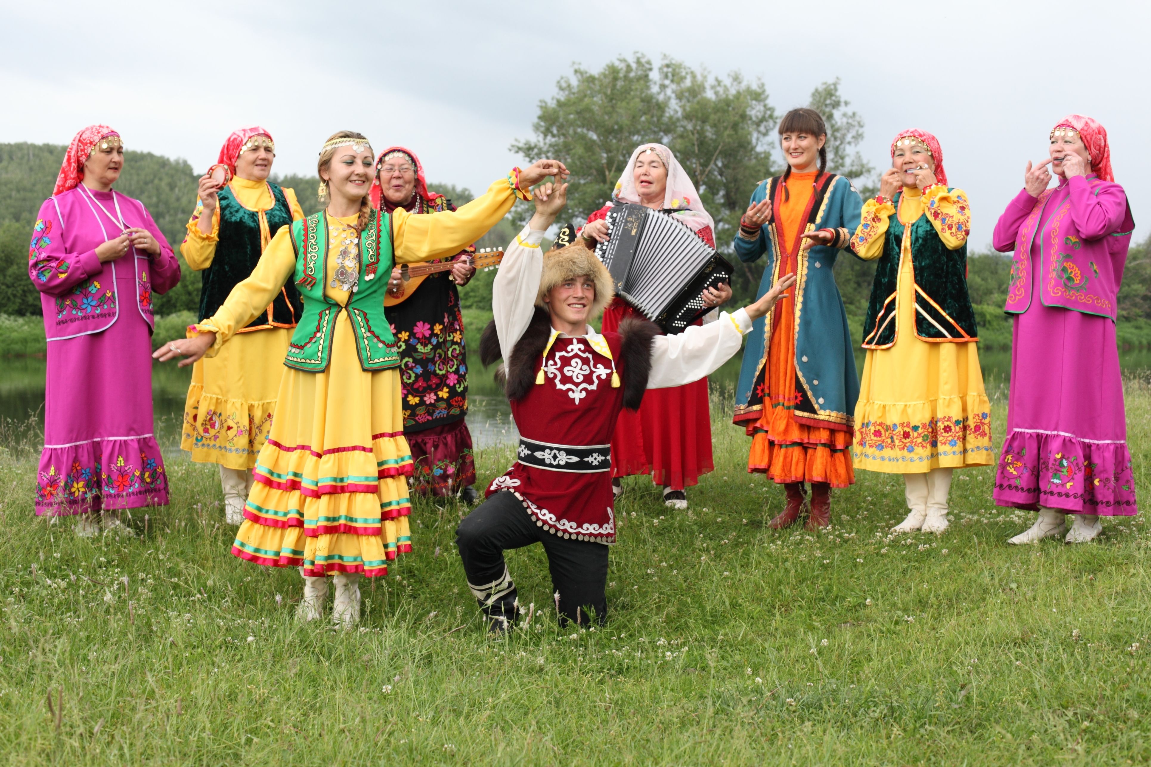 Group of people in traditional costumes enjoying folk dance and music in a field