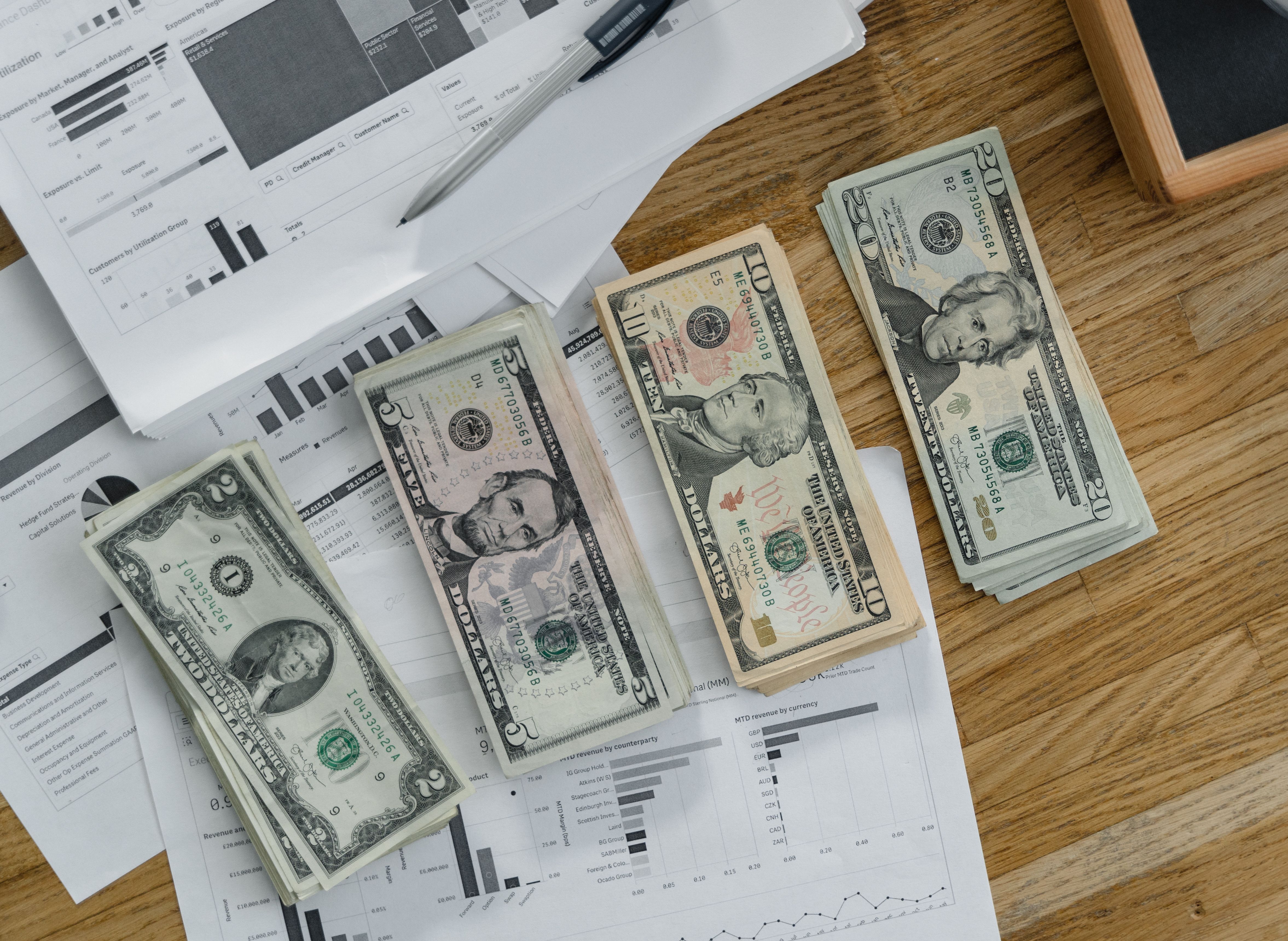 Stacks of dollar banknotes over financial reports and documents on a desk