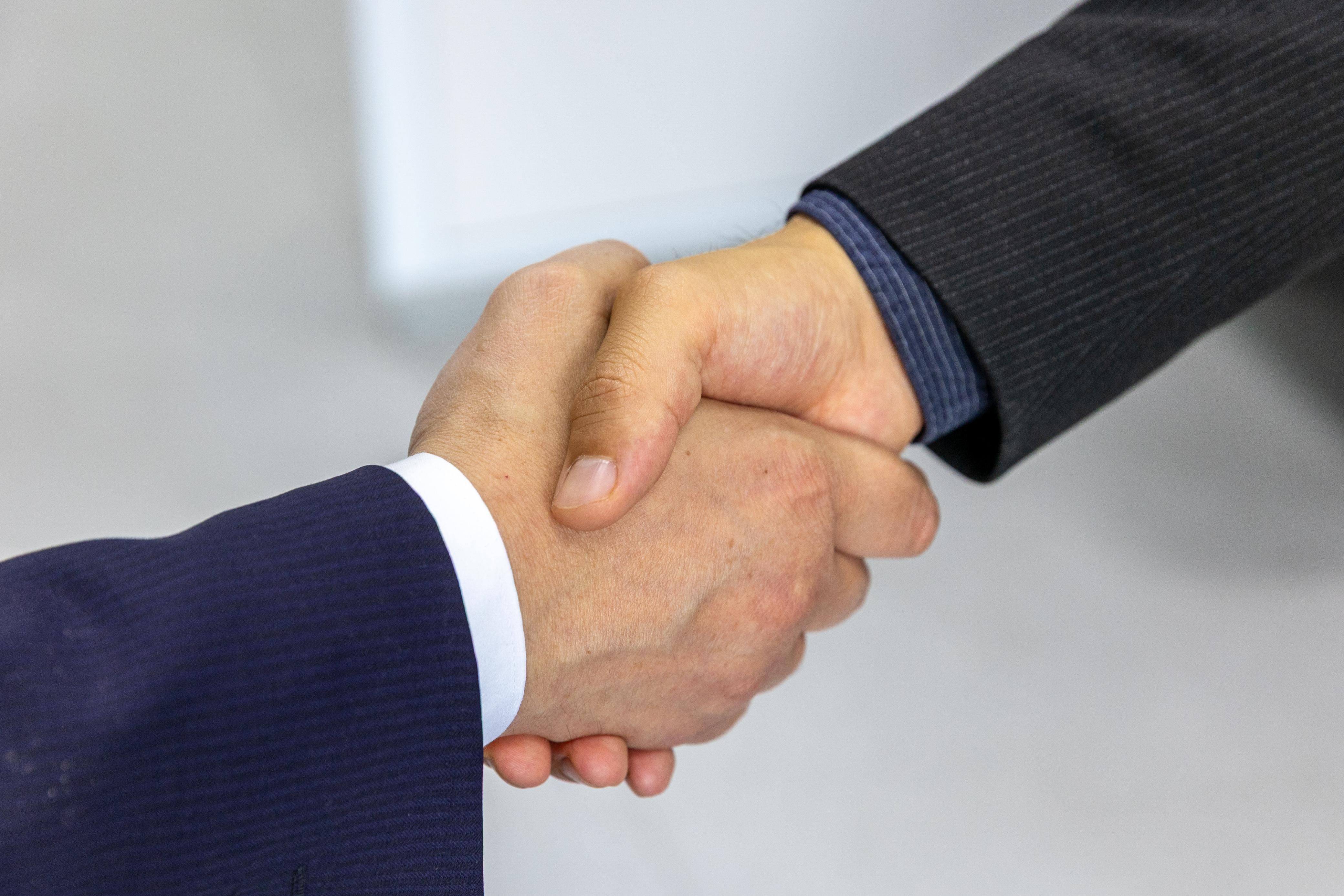 Close-up of two businessmen shaking hands symbolizing a litigation funding agreement